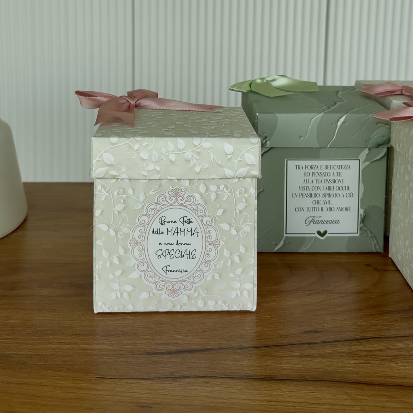 Scatole regalo personalizzate per la festa della Mamma con fiocchi in raso rosa e verde salvia, decorate con etichette su misura con dedica firmata